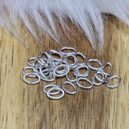 Das Bild zeigt 30 ovale, offenen Biegeringe in versilbert mit der Abmessung 5,4 x 4mm. Diese Verbindungsringe sind ein unverzichtbares Zubehör für die Schmuckherstellung. Ideal um Charms und Verschlüsse zuverlässig zu befestigen.
