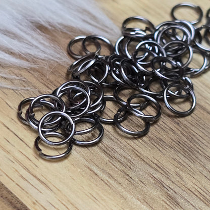 Das Bild zeigt 50 offene Biegeringe in gunmetal black mit einem Durchmesser von 6mm. Die Verbindungsringe sind ein unverzichtbares Zubehör für die Schmuckherstellung. Ideal um Charms und Verschlüsse zuverlässig zu befestigen.