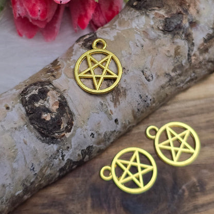 Das Bild zeigt Anhänger in Form eines invertierten Pentagramms, die in vergoldeter Ausführung gestaltet sind. Jeder Anhänger ist in einem geschlossenen Ring gefasst und hat eine Größe von etwa 16 x 13 mm. Die Oberfläche der Anhänger glänzt und reflektiert das Licht, wodurch ein eleganter und ansprechender Effekt entsteht. Die geometrische Form des invertierten Pentagramms vermittelt eine mystische Aura und verleiht den Anhängern einen besonderen Charakter.