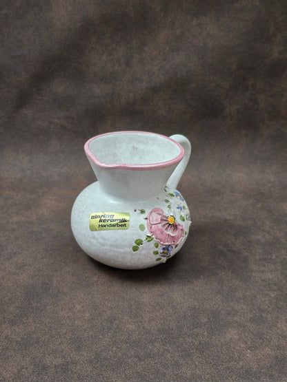 Handgefertigter Vintage-Dekokrug aus Ainring Keramik mit floralem Relief, matter Glasur und Originalaufkleber, deutsche Kunstkeramik der 1960er–1970er Jahre.