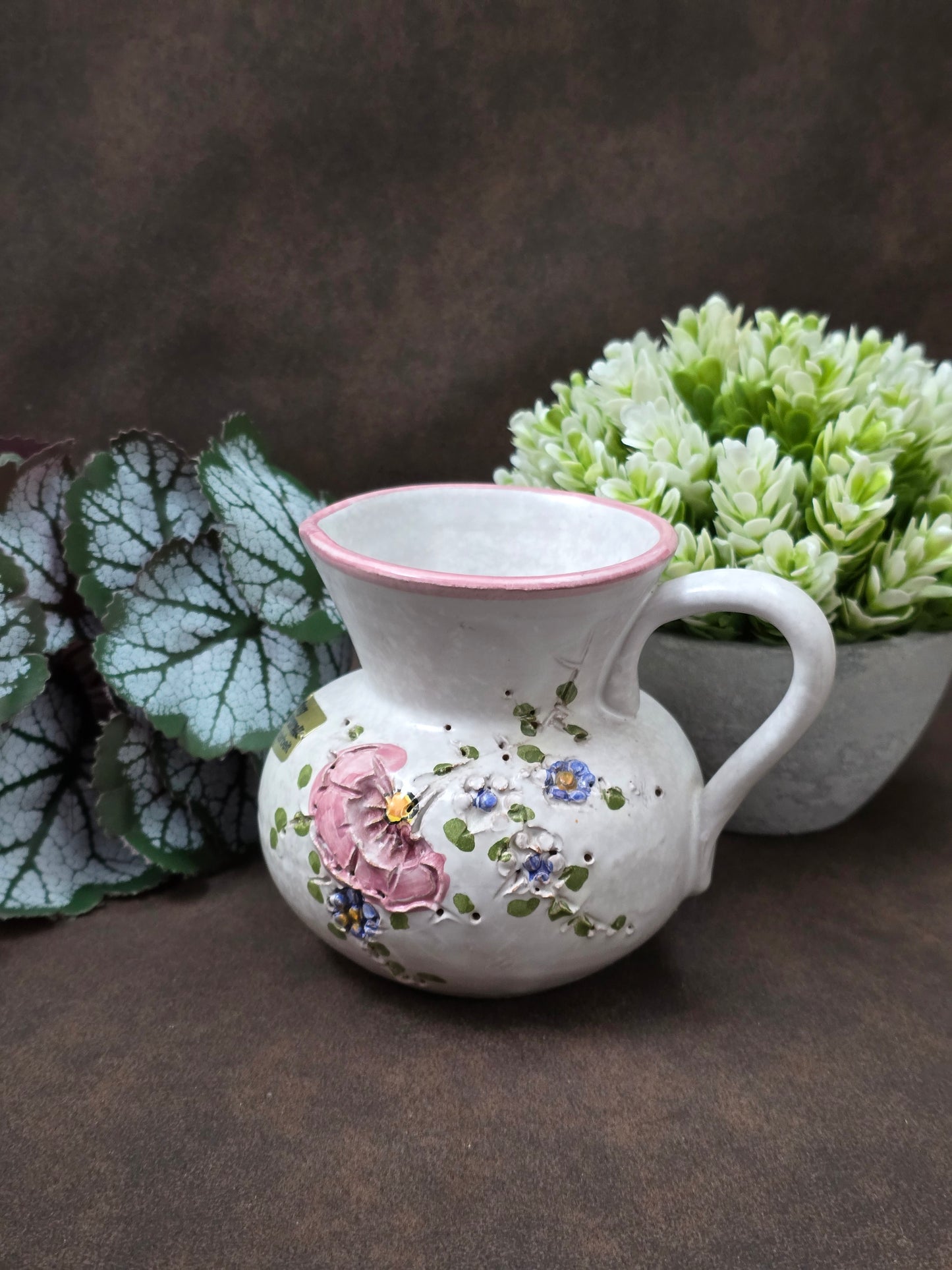 Handgefertigter Vintage-Dekokrug aus Ainring Keramik mit floralem Relief, matter Glasur und Originalaufkleber, deutsche Kunstkeramik der 1960er–1970er Jahre.