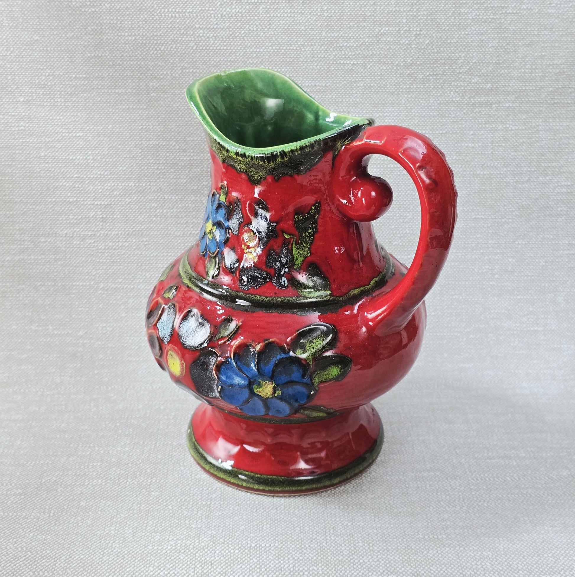 Roter Bay Keramik Krug mit reliefierten Blumen, West German Pottery 1960er, grün glasierte Innenfläche, Sammlerobjekt mit kleinem Chip am Bodenrand.