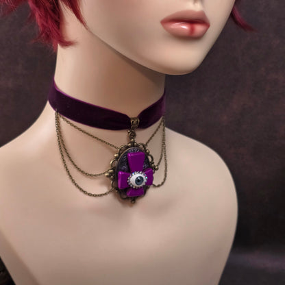 Handgefertigter Samtchoker mit invertiertem Kreuz, Auge & Strass – violett, antik-bronze, Unikat im Gothic-Stil. Für Rituale, Festivals & dunkle Seelen.