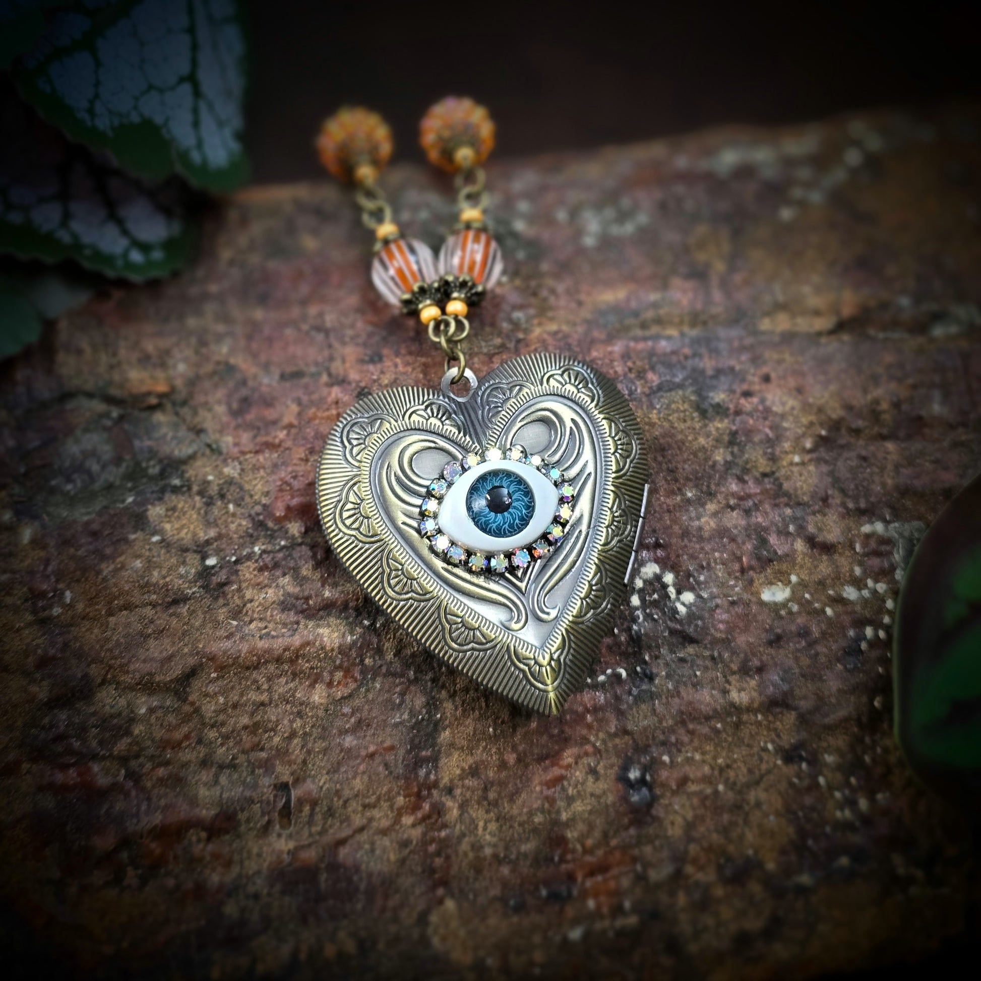 Herzmedaillon-Kette mit skurrilem Auge & Strass. Orange & Bronze, handmade & einzigartig. Mit Hakenverschluss & geheimnisvollem Look. Für alle, die das Besondere lieben.