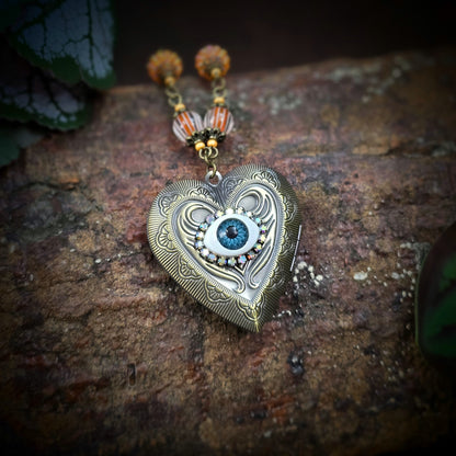 Herzmedaillon-Kette mit skurrilem Auge & Strass. Orange & Bronze, handmade & einzigartig. Mit Hakenverschluss & geheimnisvollem Look. Für alle, die das Besondere lieben.