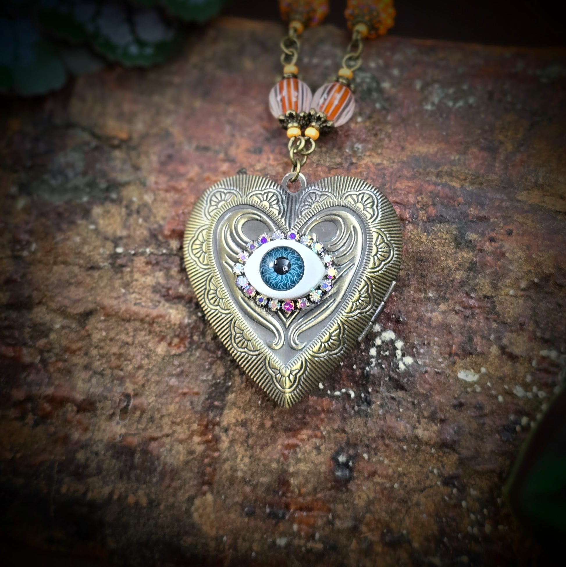 Herzmedaillon-Kette mit skurrilem Auge & Strass. Orange & Bronze, handmade & einzigartig. Mit Hakenverschluss & geheimnisvollem Look. Für alle, die das Besondere lieben.