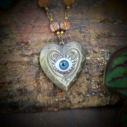 Herzmedaillon-Kette mit skurrilem Auge & Strass. Orange & Bronze, handmade & einzigartig. Mit Hakenverschluss & geheimnisvollem Look. Für alle, die das Besondere lieben.