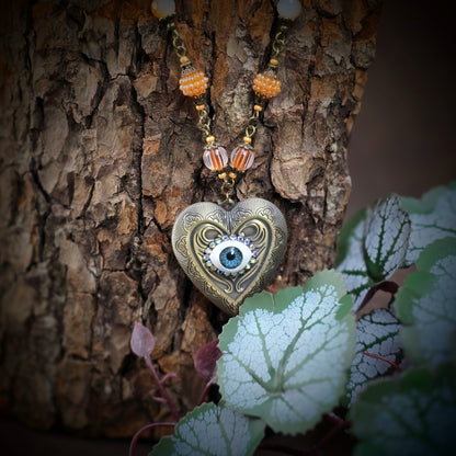 Herzmedaillon-Kette mit skurrilem Auge & Strass. Orange & Bronze, handmade & einzigartig. Mit Hakenverschluss & geheimnisvollem Look. Für alle, die das Besondere lieben.