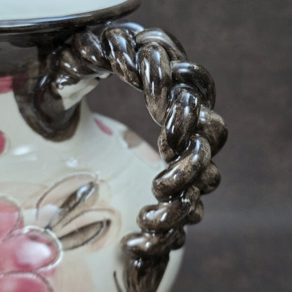 Handbemalter italienischer Keramikkrug mit floralen Ornamenten und geflochtenem Henkel, Vintage ca. 1960er–1980er Jahre.