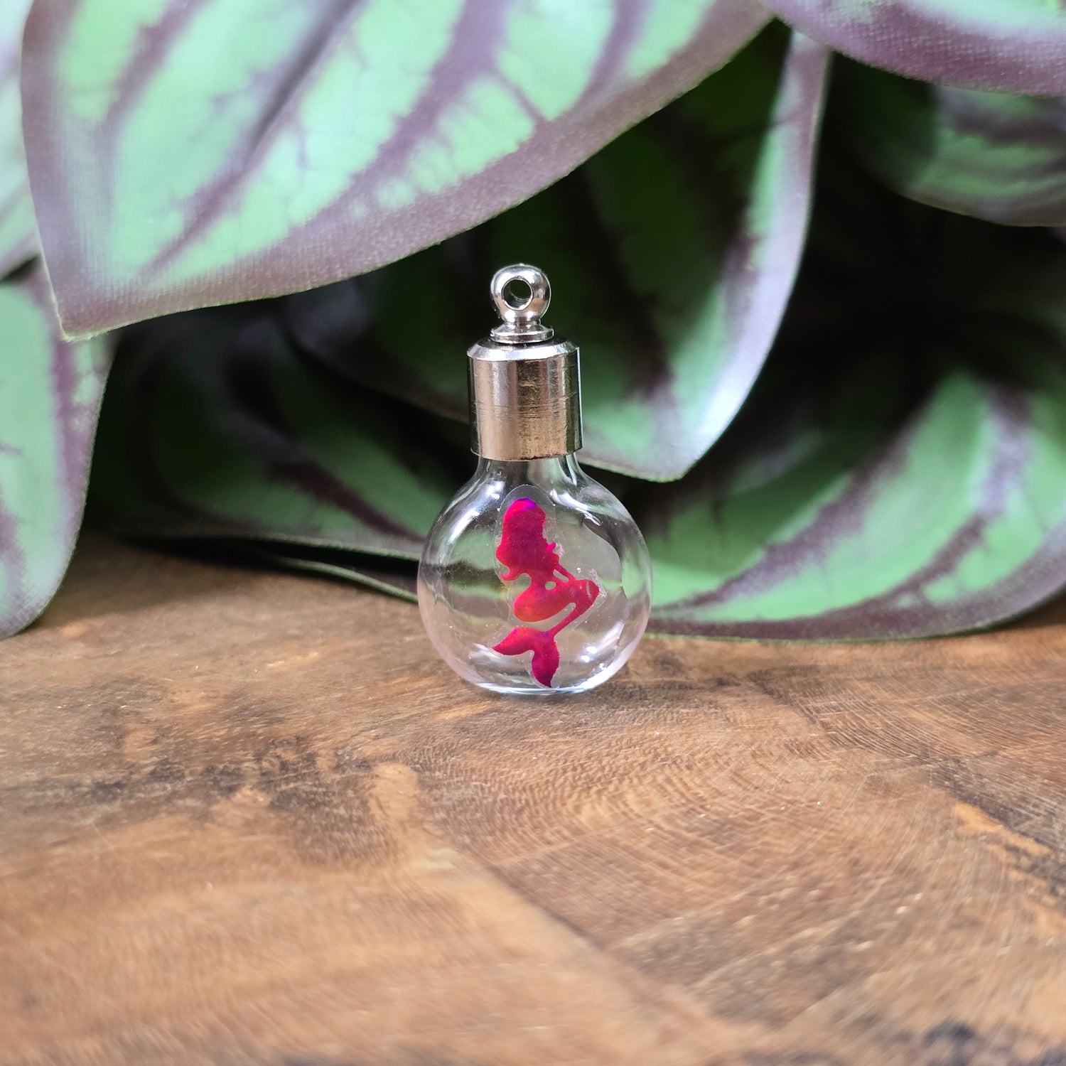 Kleine Glasflasche mit Schraubverschluss und pinkem Meerjungfrau-Motiv, ideal als Kettenanhänger und tragbare Parfümflasche.