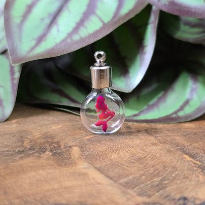 Kleine Glasflasche mit Schraubverschluss und pinkem Meerjungfrau-Motiv, ideal als Kettenanhänger und tragbare Parfümflasche.