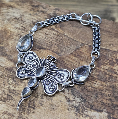 Nahaufnahme eines Armbands aus .925 Silber mit einer filigranen Libelle und Zirkoniasteinen, versehen mit einem Toggle-Verschluss, ca. 4,9 x 4,2 cm Länge.