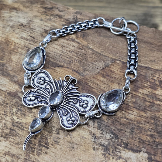 Nahaufnahme eines Armbands aus .925 Silber mit einer filigranen Libelle und Zirkoniasteinen, versehen mit einem Toggle-Verschluss, ca. 4,9 x 4,2 cm Länge.
