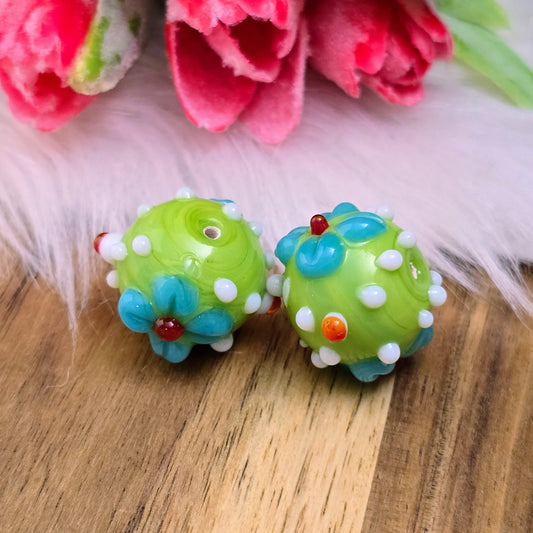Zwei grüne Glasperlen mit Blumenmuster & Bumps – handgefertigt in Indien. Ideal für Ketten, Armbänder & mehr. Jede Perle ein Unikat!