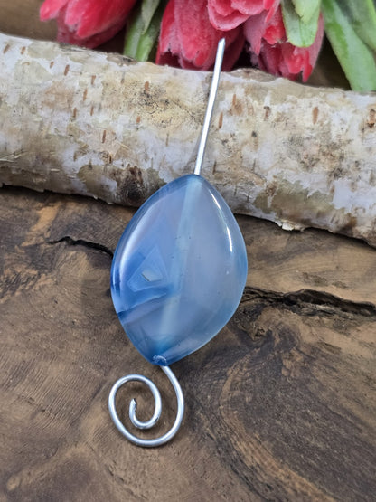 Blaue Achat-Navetteperle auf einem silbernen Schmuckdraht aufgefädelt als Anwendungsbeispiel für Anhänger oder Ketten.
