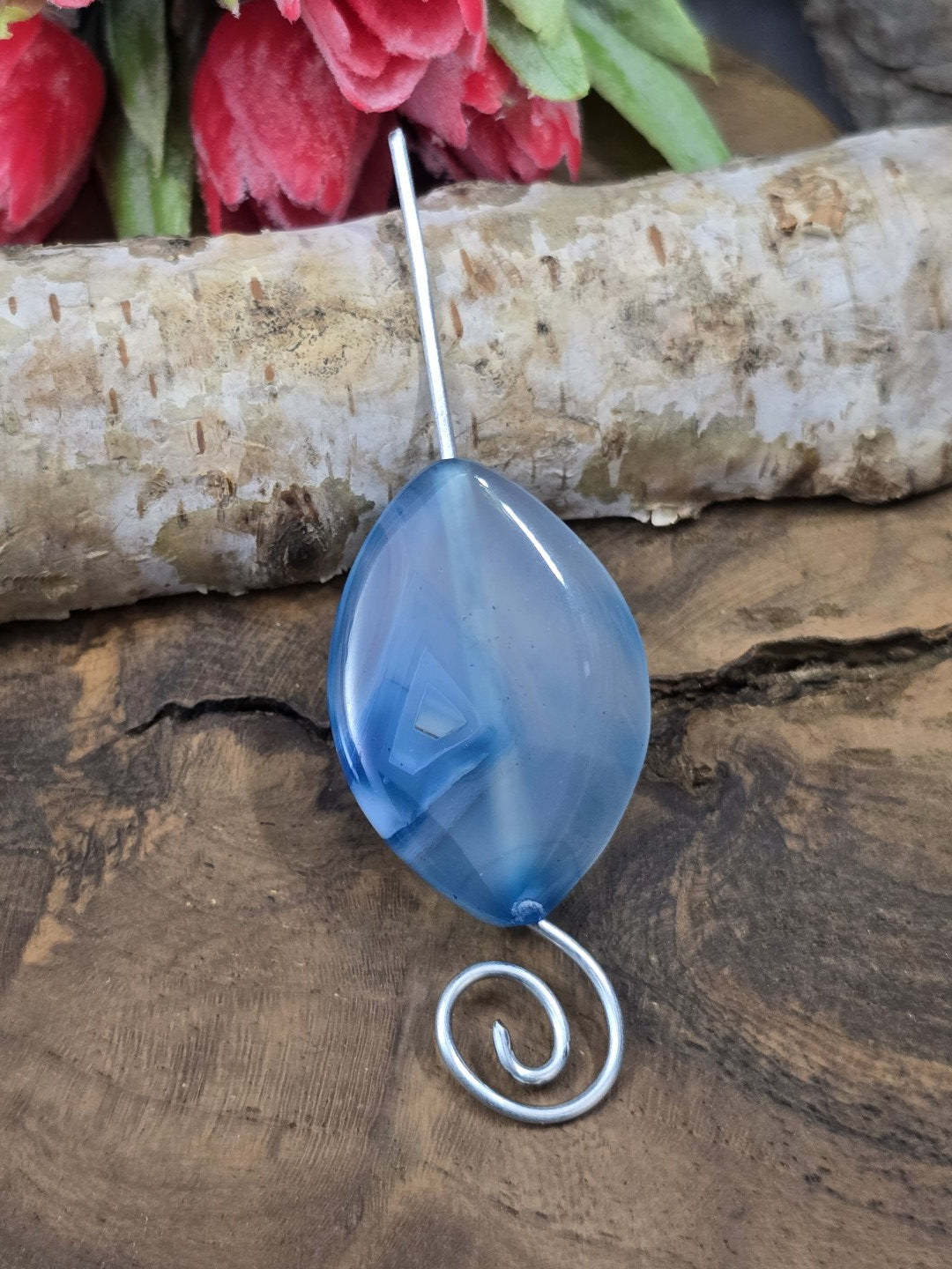 Große blau gebänderte Achat-Perle (34x24 mm) auf gebogenem Drahtstift zur Veranschaulichung der vertikalen Bohrung.