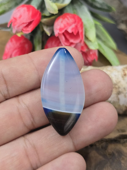 Große Achat-Navetteperle in Blau (39 mm) auf den Fingerspitzen als Größenvergleich für Statement-Schmuck und Ketten.
