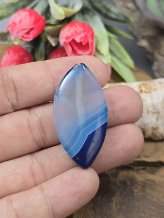 Große blau gebänderte Achat-Navetteperle (39 mm) auf einer Handfläche als präziser Größenvergleich für die Schmuckherstellung.