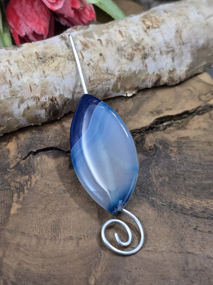 Blaue Achat-Centerperle in Navette-Form auf silbernem Schmuckdraht aufgefädelt als Anwendungsbeispiel für Kettenanhänger.
