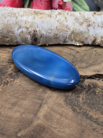 Seitliche Perspektive der flach liegenden Achat-Navetteperle in Blau mit glänzendem Lichtreflex.
