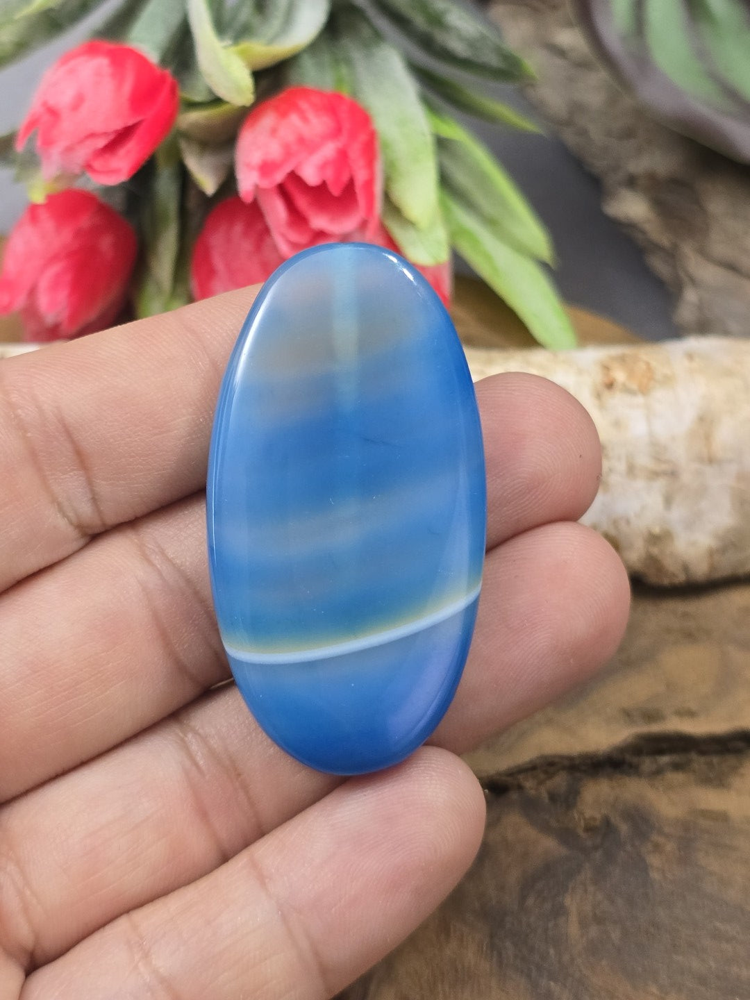 Große blau gebänderte Achat-Navetteperle (48 mm) auf der Handfläche gehalten als Größenvergleich für die Schmuckherstellung.