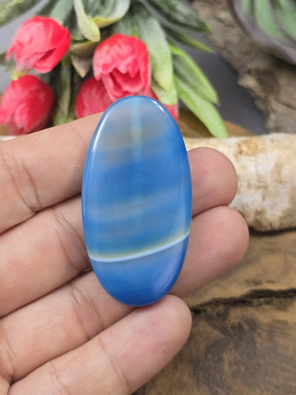 Große blau gebänderte Achat-Navetteperle (48 mm) auf der Handfläche gehalten als Größenvergleich für die Schmuckherstellung.