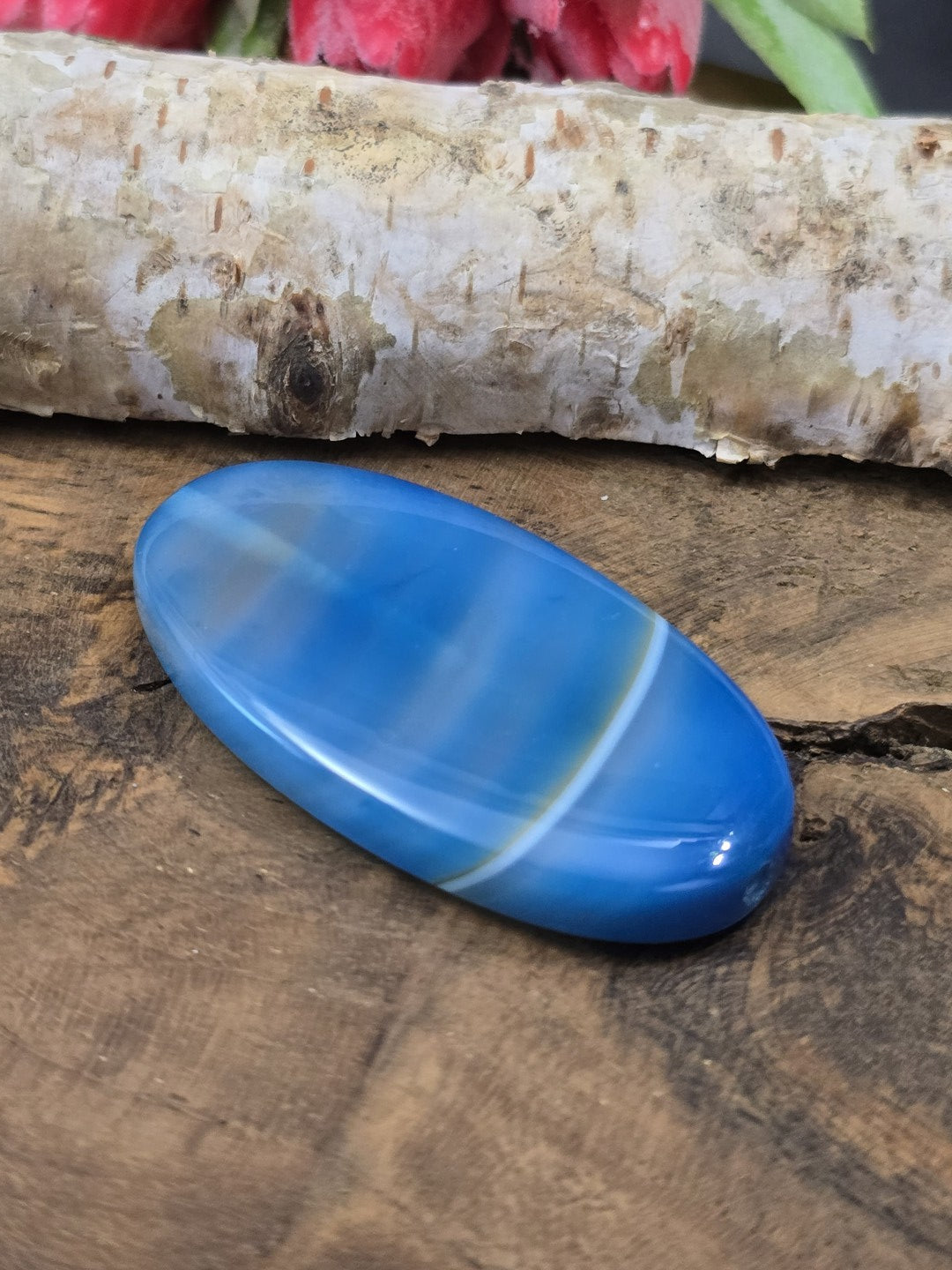 Seitliche Perspektive der flach liegenden gebänderten Achat-Navetteperle in Blau mit sichtbarem Loch-Eingang.