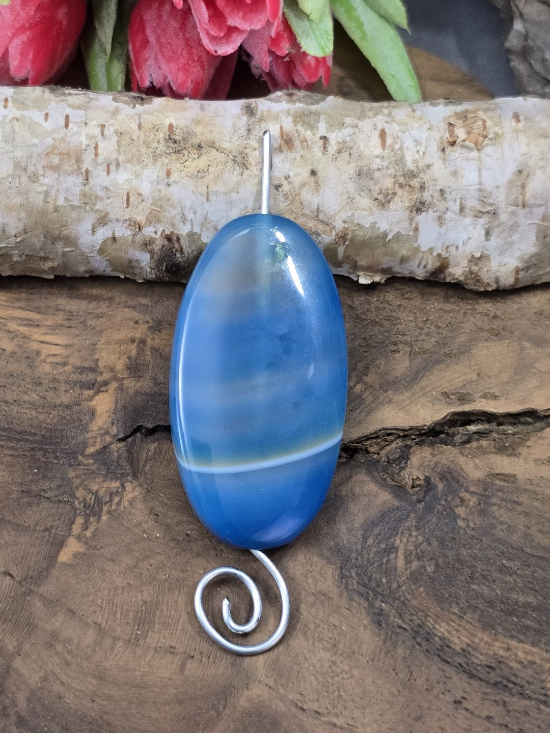 Blau gebänderte Achat-Centerperle (48 mm) auf silbernem Schmuckdraht aufgefädelt als Anwendungsbeispiel für Anhänger.