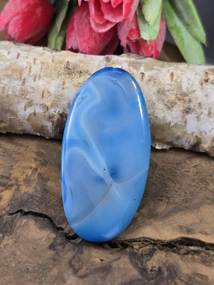 Blaue gemusterte Achat-Centerperle (50 mm) in Navette-Form mit hellen Bändern auf Holz vor Birkenstamm.