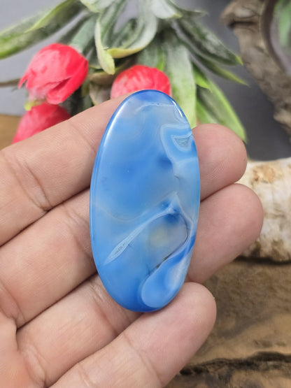 Große blau gemusterte Achat-Navetteperle (50 mm) auf der Handfläche gehalten als Größenvergleich für die Schmuckherstellung.