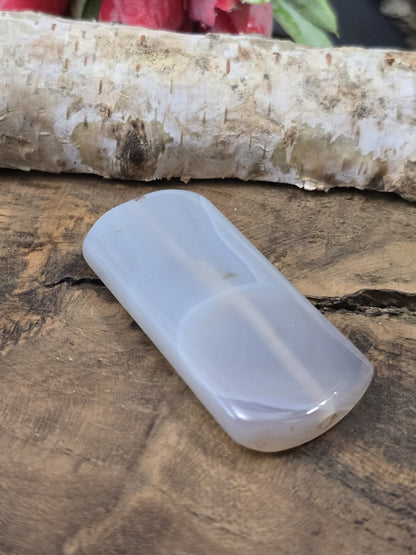 Seitliche Perspektive der flach liegenden semitransparenten Achat-Pillowperle mit sichtbarem Loch-Eingang der Fädelbohrung.