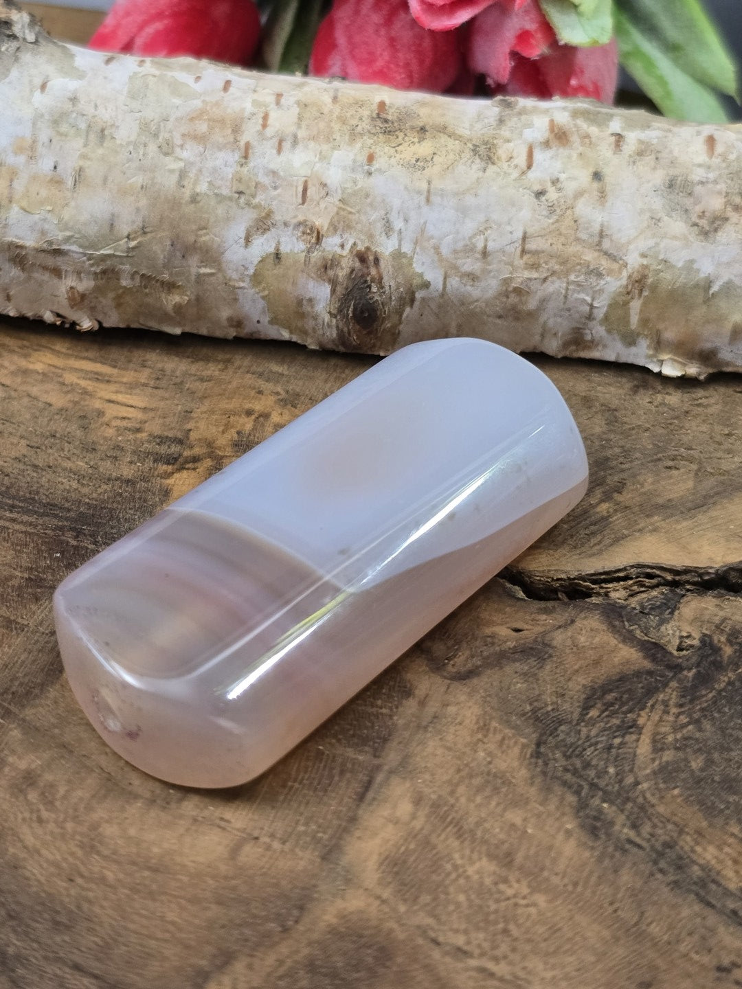 Liegende rosa Achat-Centerperle (50 mm) auf Holz zur Darstellung des Seidenglanzes und der Fädelbohrung.