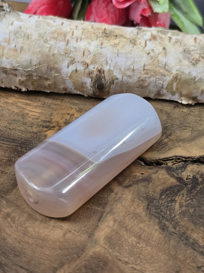 Liegende rosa Achat-Centerperle (50 mm) auf Holz zur Darstellung des Seidenglanzes und der Fädelbohrung.
