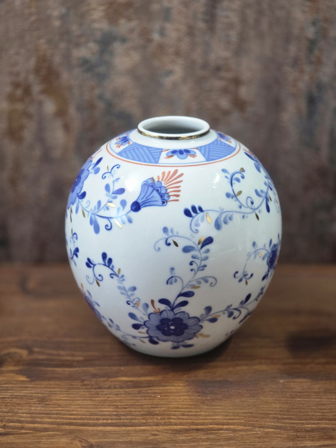 Vintage Kugelvase aus weißem Porzellan mit kobaltblauen Blüten, feinen Ranken und orangefarbenen Details in seitlicher Ansicht