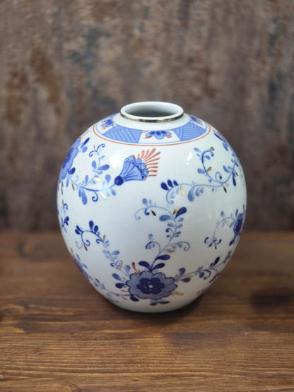 Vintage Kugelvase aus weißem Porzellan mit kobaltblauen Blüten, feinen Ranken und orangefarbenen Details in seitlicher Ansicht