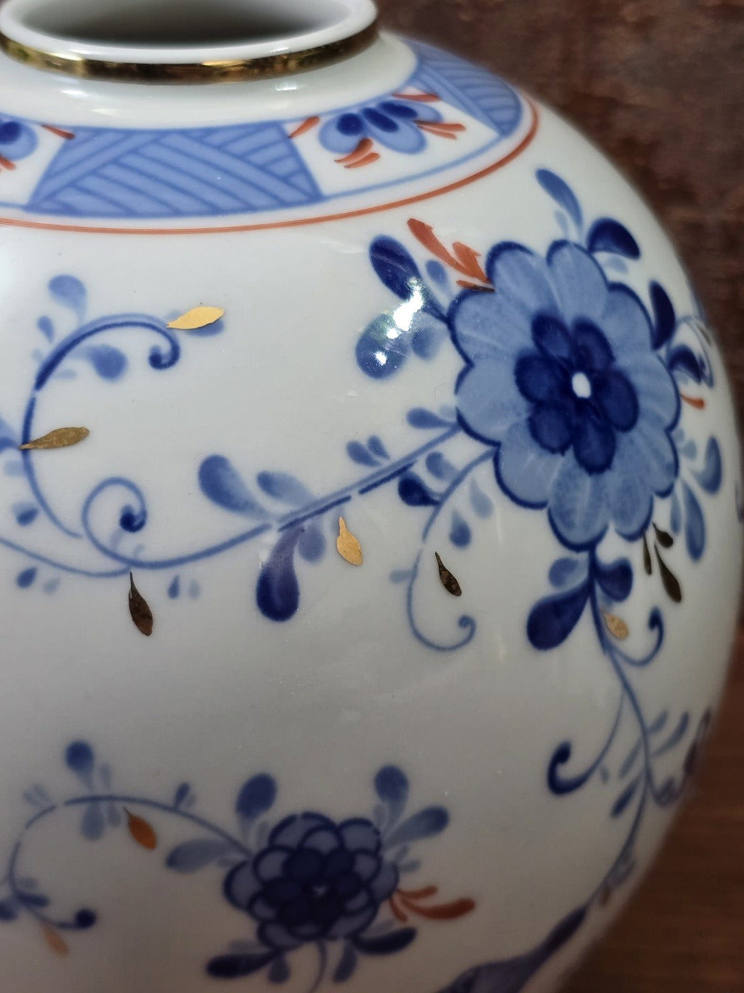 Vintage Kugelvase mit großer blauer Blüte, geschwungenen Ranken und kleinen goldfarbenen Blattdetails in Nahaufnahme