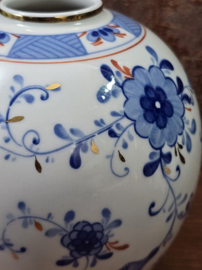 Vintage Kugelvase mit großer blauer Blüte, geschwungenen Ranken und kleinen goldfarbenen Blattdetails in Nahaufnahme