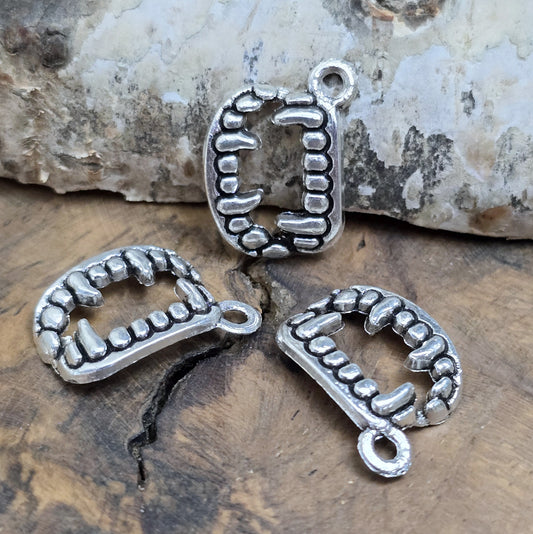 Das Bild zeigt 3 Charms Anhänger Vampirzähne in antik silberfarbig, 18mm. Ideal für die Schmuckherstellung.