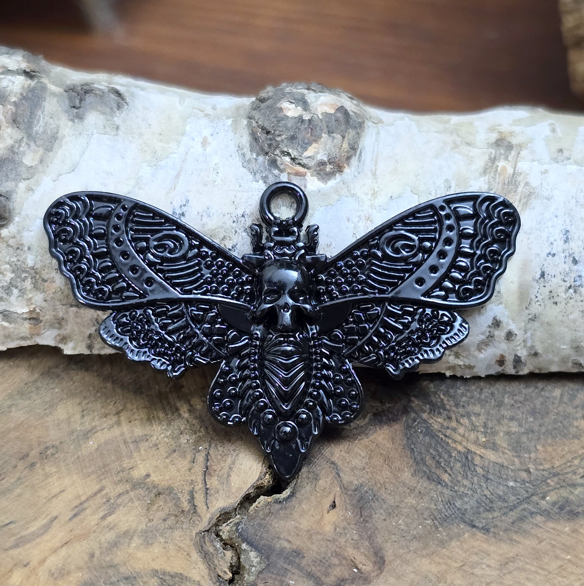 Das Bild zeigt einen Anhänger mit schwarzer Beschichtung. Mit 27 mm Breite und einer stabilen Öse eignet er sich perfekt für Ketten, Choker und andere individuelle Schmuckstücke.