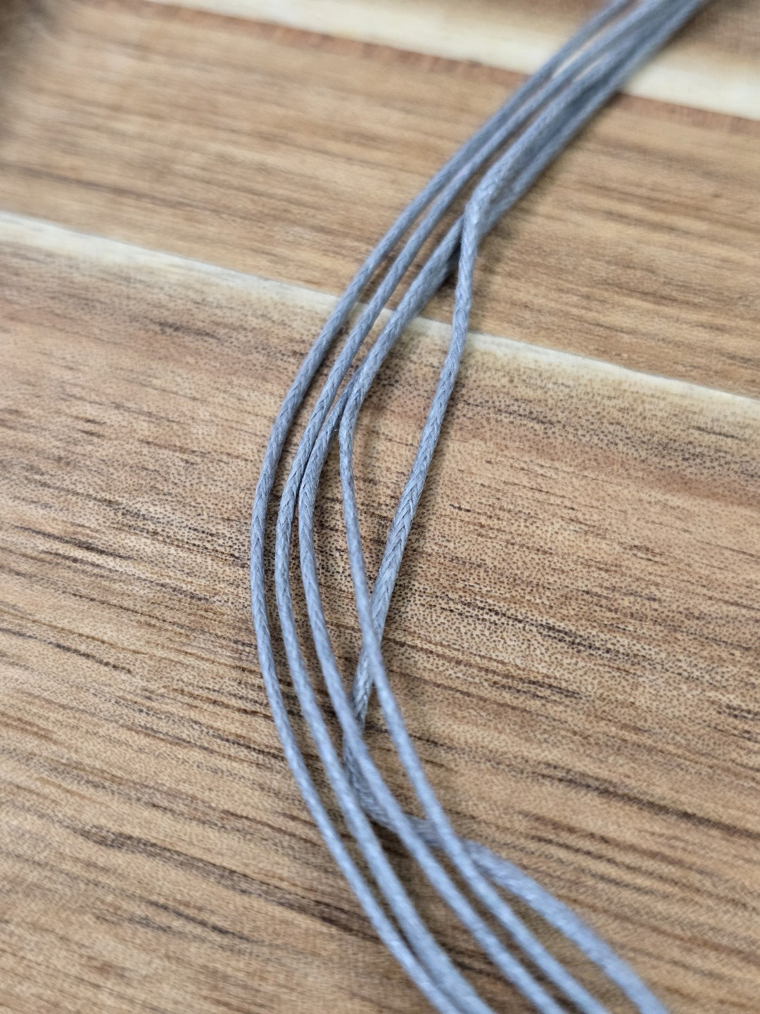 Nahaufnahme der einzelnen grauen Kordelfäden einer 5-fädigen Baumwollkette.