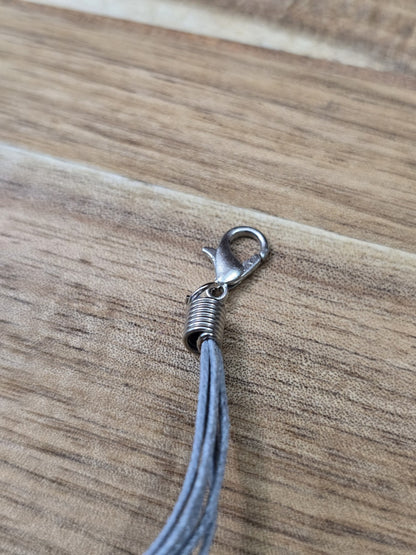 Detailansicht des silbernen Karabinerverschlusses der grauen Baumwollkette.