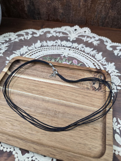 Schwarze Baumwollkette 42cm mit Silber-Karabinerverschluss und Verlängerungskette ausgelegt auf Holztablett.