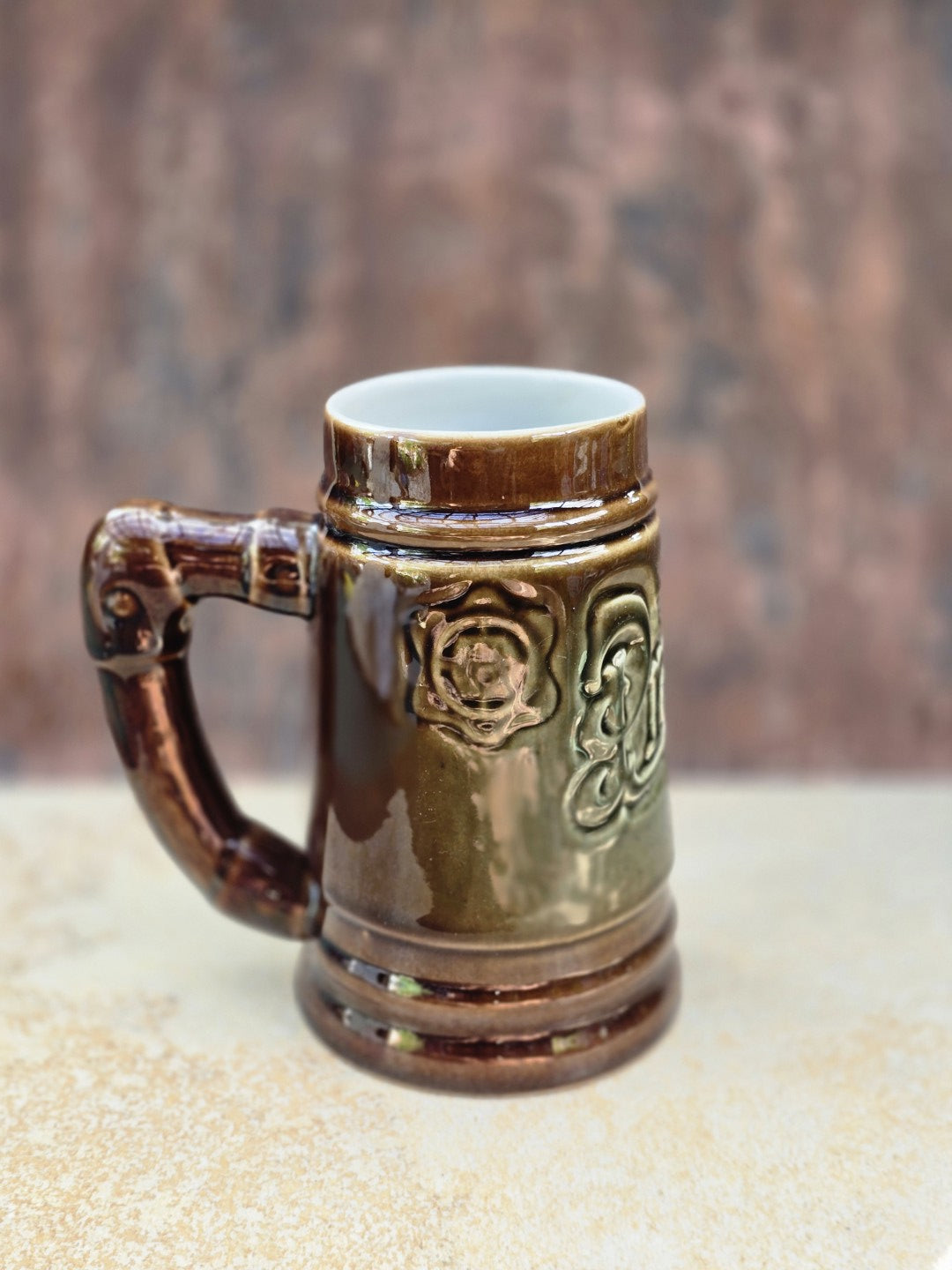 Bechyně Vintage Bierseidel mit reliefiertem Plzeňský Prazdroj Schriftzug, rustikalem Asthenkel, braun-grüner Glasur und Brückenmarke am Boden.