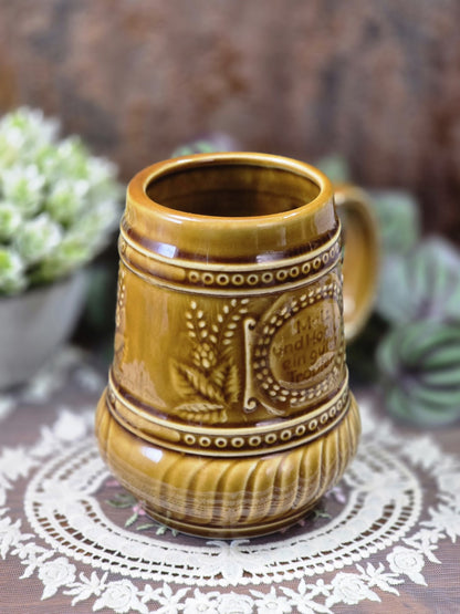 Vintage Bierkrug mit brauner glänzender Glasur, rundem Rand und reliefiertem Punktband in schräger Nahansicht