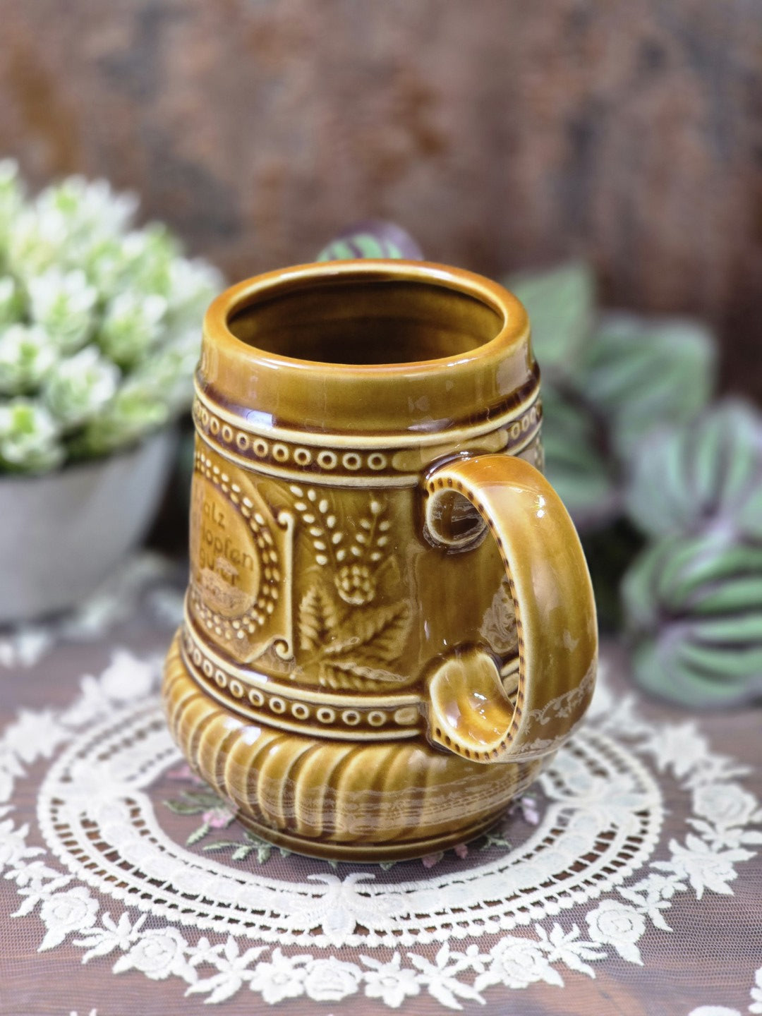 Steingut Bierkrug mit brauner Glasur, Hopfenrelief, Schriftfeld und seitlichem Henkel in seitlicher Ansicht
