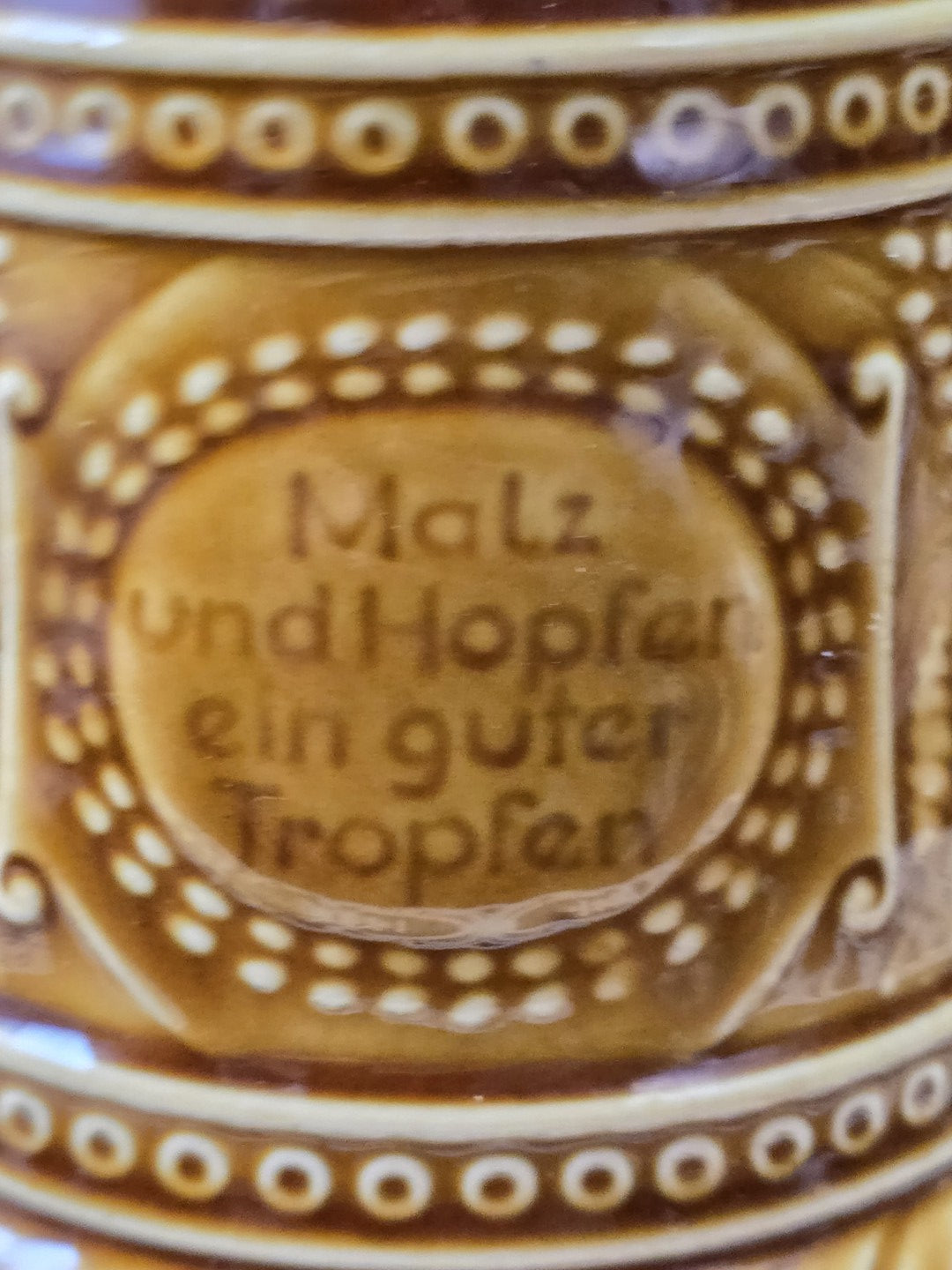 Brauner Steingut Bierkrug mit Spruch „Malz und Hopfen ein guter Tropfen“ als Nahaufnahme des Schriftfelds