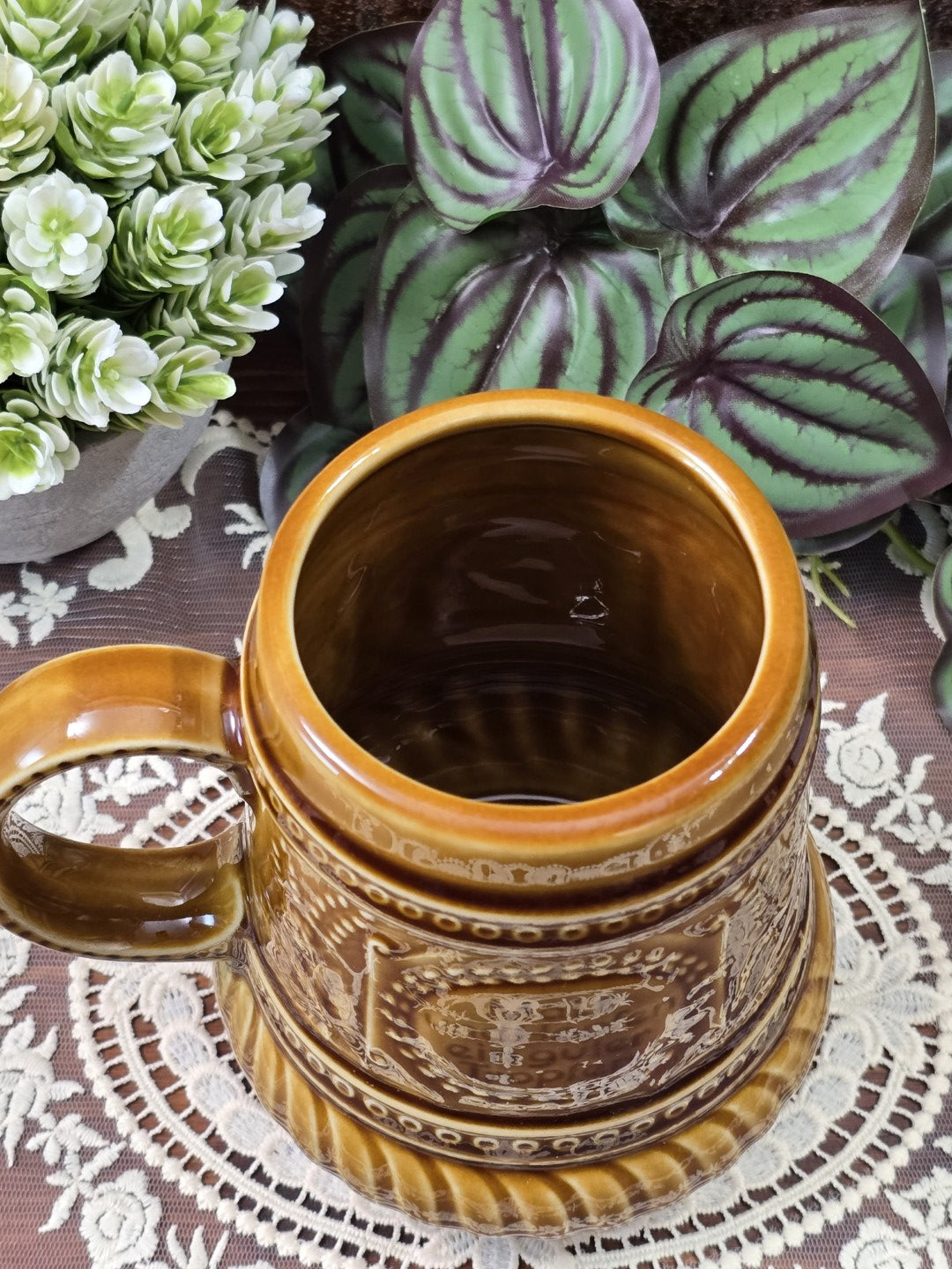Brauner Vintage Bierkrug aus Steingut mit offenem Innenraum, Henkel und Reliefdekor von oben fotografiert