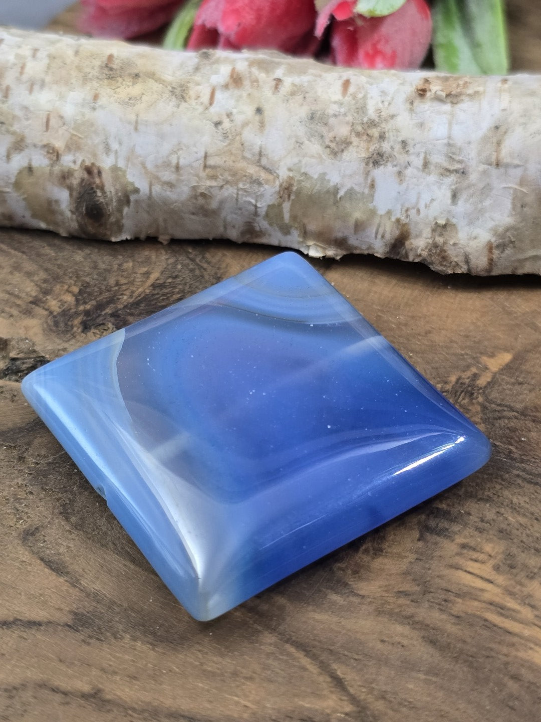 Perspektivische Seitenansicht des quadratischen blauen Achat-Pendants auf Holz mit sanftem Lichtreflex.