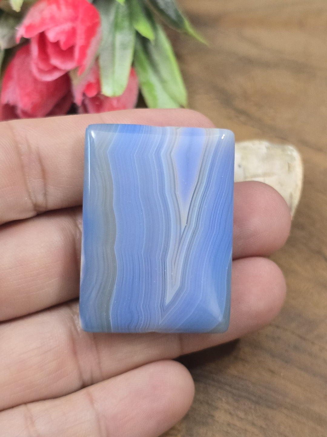 Polierter blauer Achat-Pendant in Rechteckform auf der flachen Hand als Größenvergleich für DIY-Schmuck.