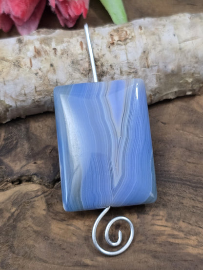 Aufgereihtes blaues Achat-Rechteck auf einem geschwungenen Metallstift zur Veranschaulichung der vertikalen Bohrung.